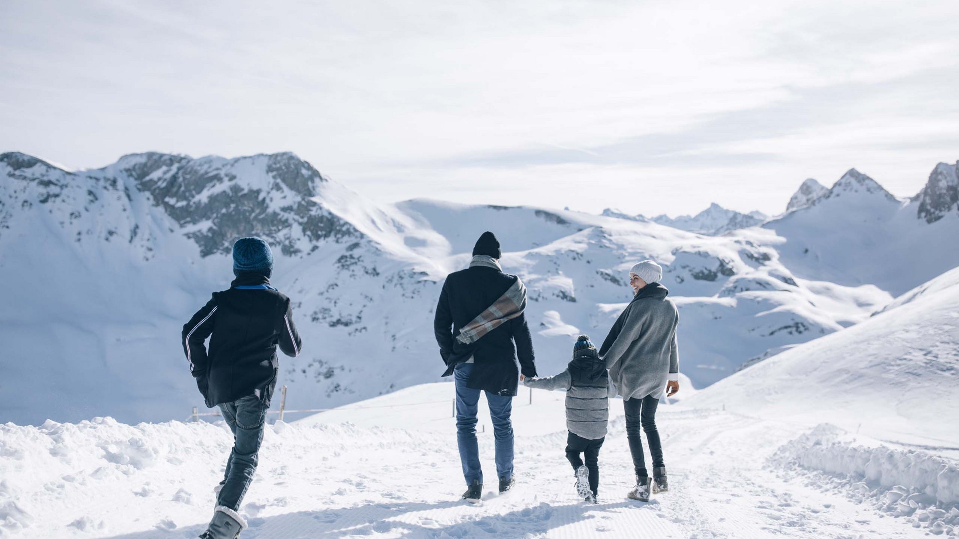 Family walking in snow with mountains in the background
